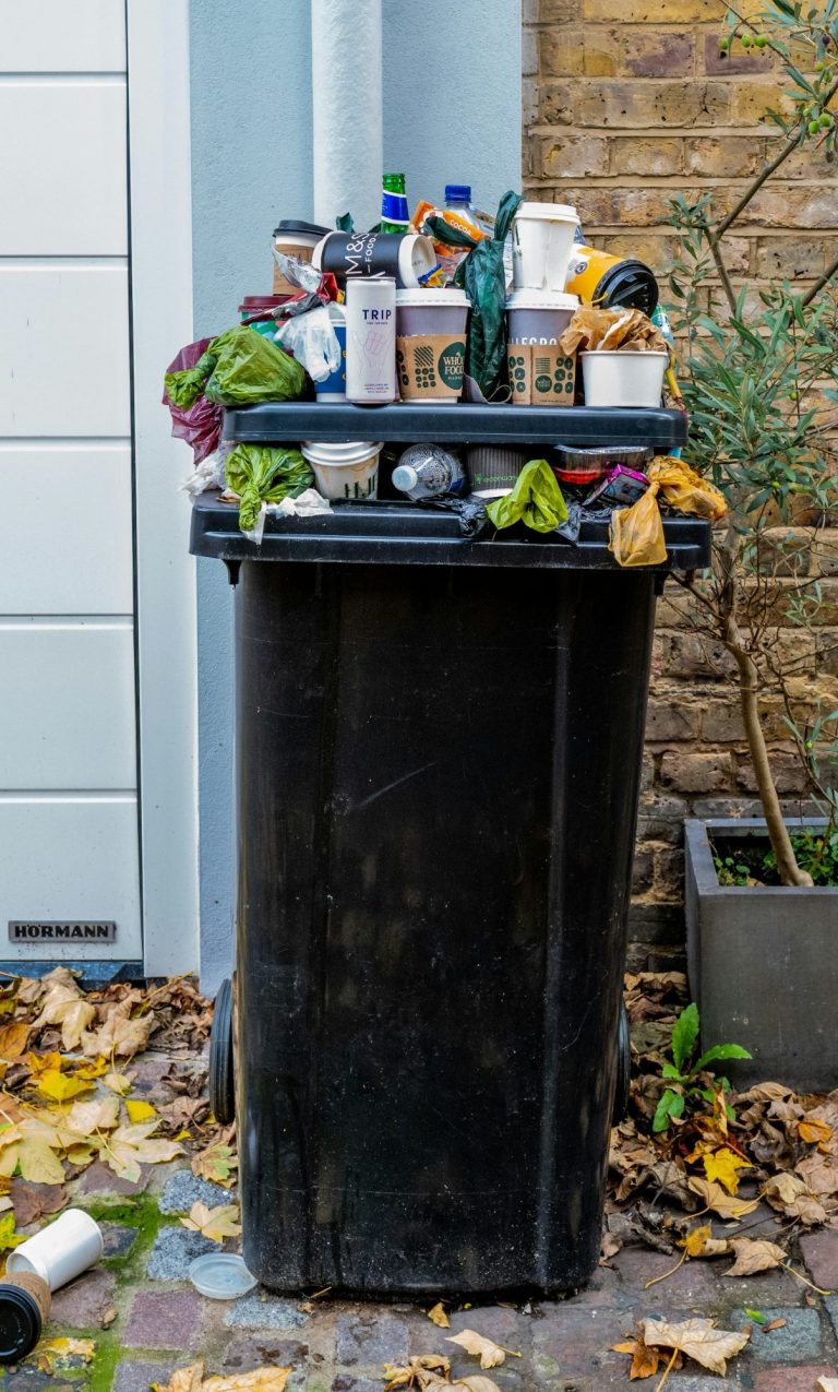 Übervolle schwarze Mülltonne im Freien